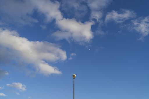 A street light under the cloudy sky during daytime