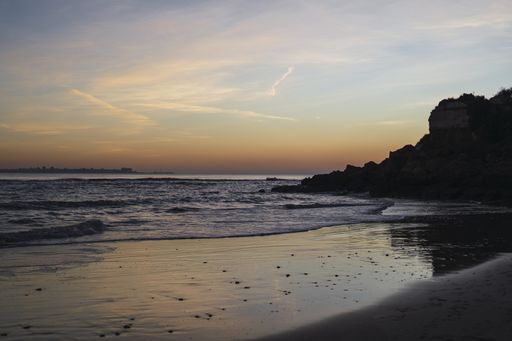 A beautiful shot of the sea waves and a cliff during sunset