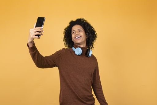A shot of a cheerful afro young man taking a selfie on the phone