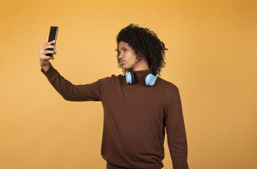 A shot of a young African American man taking a selfie with the phone