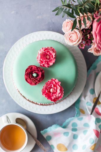 A vertical top view of a cake covered by green marzipan and delicate flowers on top