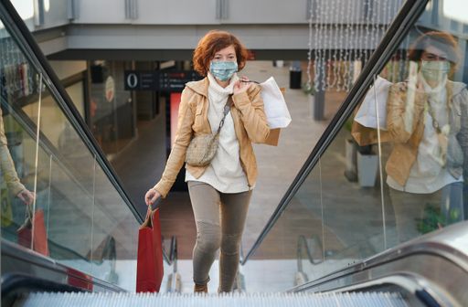A redhead female in a protective mask coming out of the metro station, moving up on the escalator