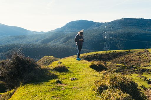 A shot of a girl in a protective medical mask standing in mountains  -  pandemic tourism