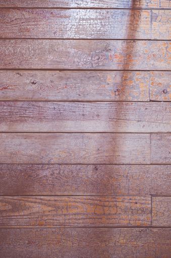 A top view closeup of a wooden floor with a shadow of an object on it
