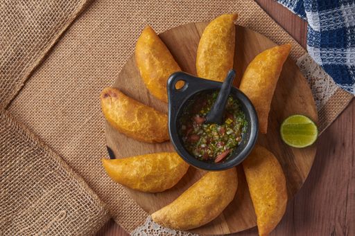 A high angle shot of delicious fried pies with vegetable filling and lime on a wooden board