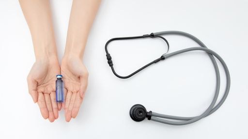 A top view of a hand holding a medicine bottle and a stethoscope on a white background