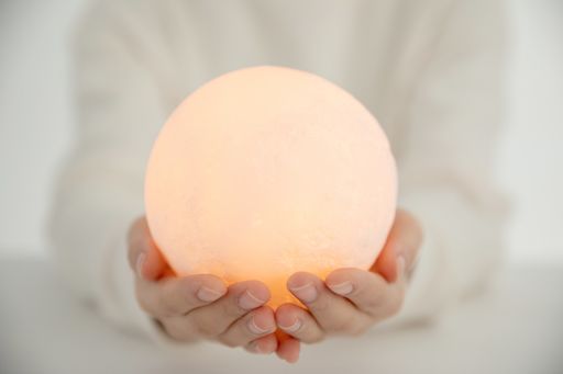 A closeup shot of hands holding an illuminated orange ball