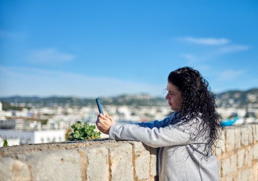 A shallow focus shot of a Hispanic female sitting using her phone outdoors