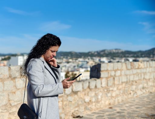 A shallow focus shot of a Hispanic female sitting using her phone outdoors