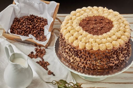 A selective focus shot of a delicious freshly baked cappuccino cake, milk, coffee beans on the table