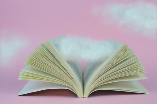 A closeup of an open book with a cloud between the pages isolated on a pink background