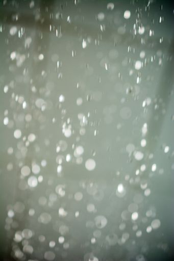 A vertical blurred shot of raindrops falling from the sky