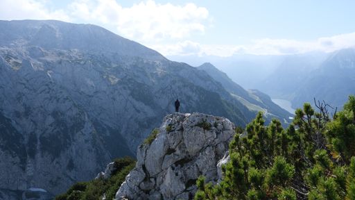 A tourist standing on top of a mountain overlooking the beautiful view in German