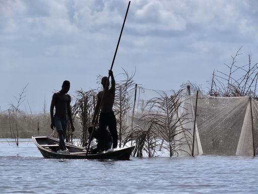 Two fishermen checking their nets in a traditional wooden boat near the village of Ganvie in Benin, West Afric