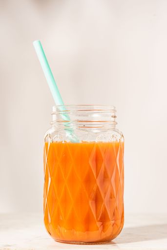 A vertical shot of orange, mango, peach smoothie in glass