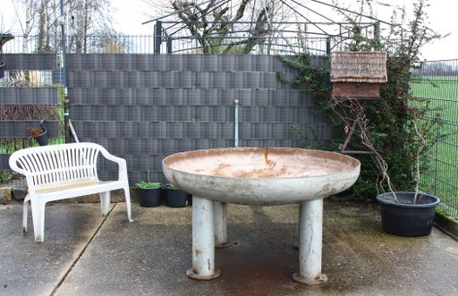 A closeup of an old rusty metal table-shaped garden pot during the rain