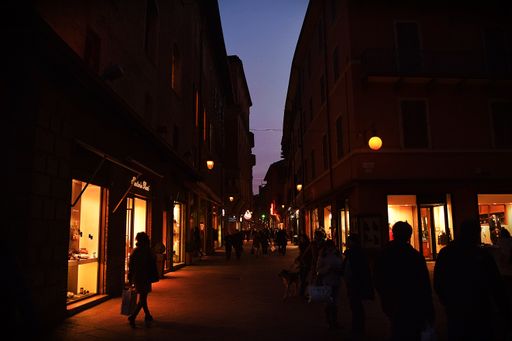 A busy street in the center of Bologna, with shops and businesses, lit up at night. Bologna, Italy