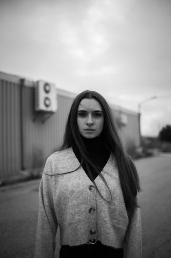 A vertical grayscale shot of a Caucasian young woman with a thoughtful sad face