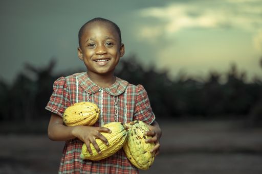 A selective focus shot of a cute happy African-American child with fruits in hands
