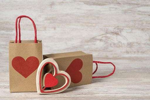 A heart-shaped wooden decor and gift paper bags on the table, festive shopping for St. Valentine's day