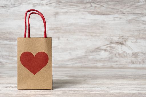 A gift paper bag on the table, shopping for St. Valentine's day, background with copy space