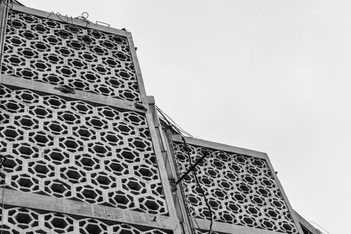 A greyscale low angle shot of a building with a patterned facade