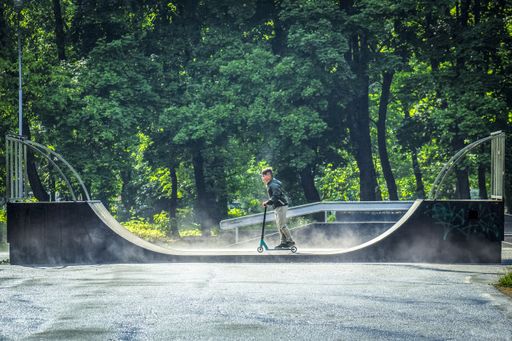 Little boy ride the bike in the skatepark located in the summer park