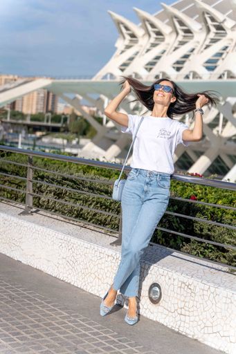 A young brunette woman casually dressed and taking a leisurely stroll along a pathway in a city street
