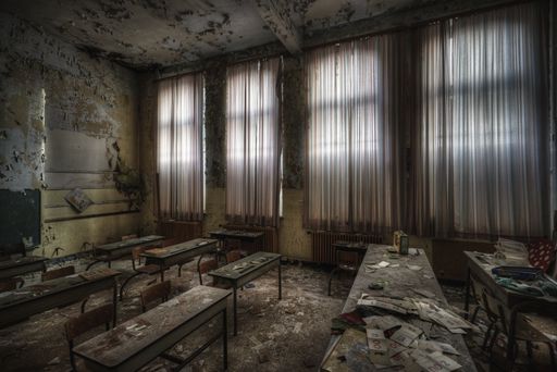 A ruined classroom with broken desks and walls of an abandoned school