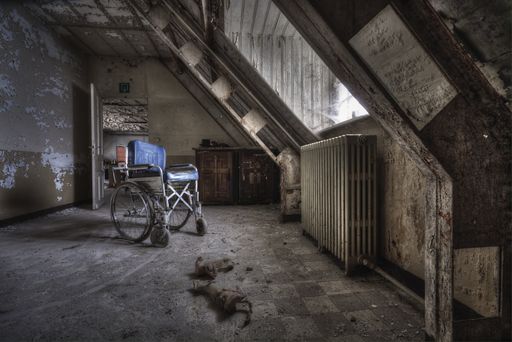 An old wheelchair in a ruined room with dirty walls of an abandoned building