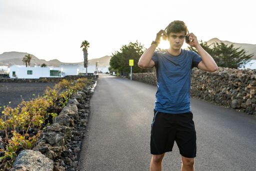 A young Caucasian man listening to music with headphones in the street during the sunrise