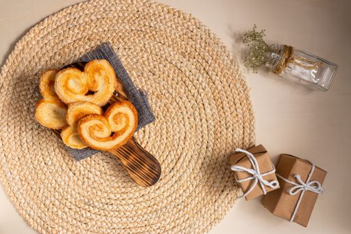A romantic breakfast on St. Valentine's day - heart-shaped palmier cookies served on a board on the round jute table mat