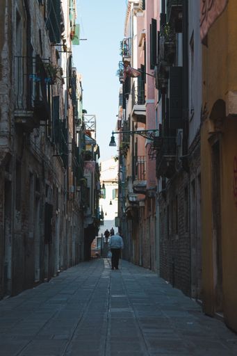 A vertical shot of a narrow alleyway in the middle of the buildings at Venice Italy