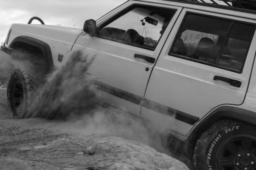 An image of a white jeep trying to move in the soil in black and white.