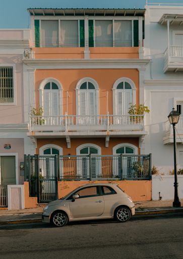 A vertical shot of a car parked in front of a colorful building