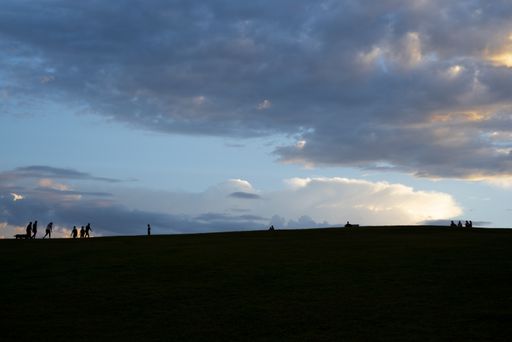 A group of people walking in the evening under the beautiful cloudy sky during sunset