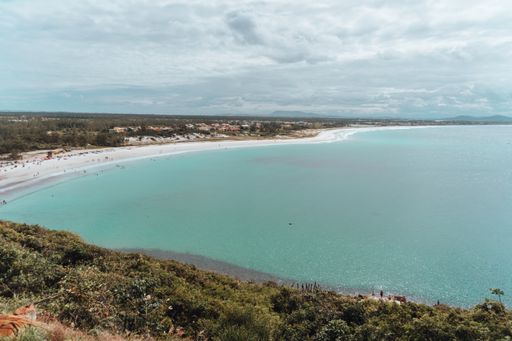 A landscape of the sea surrounded by greenery under the sunlight and a blue sky