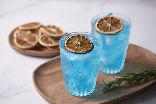 A high angle shot of two glasses of Blue Lagoon cocktails and dried lemons on a wooden tray