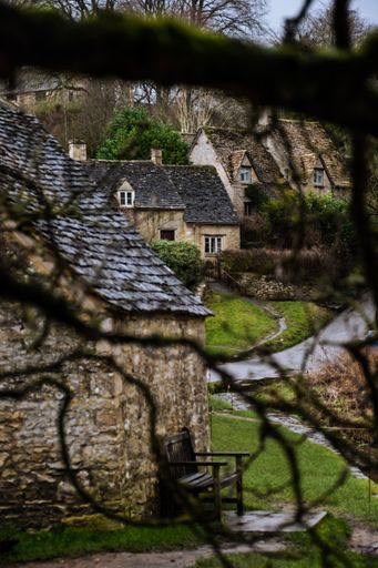 A beautiful vertical view of small houses through branches in a garden