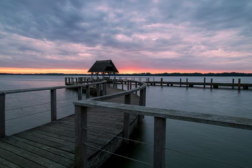 A beautiful shot of a long wooden pier over the sea at sunset