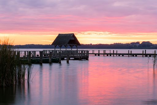 A beautiful shot of a long wooden pier with the sunset sky colors reflecting in the water