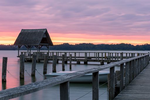 A beautiful shot of a long wooden pier with the sunset sky colors reflecting in the water
