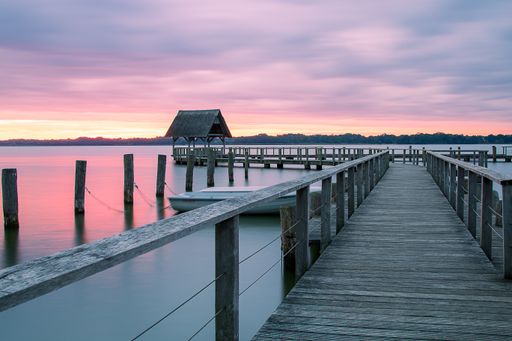 A beautiful shot of a long wooden pier with the sunset sky colors reflecting in the water