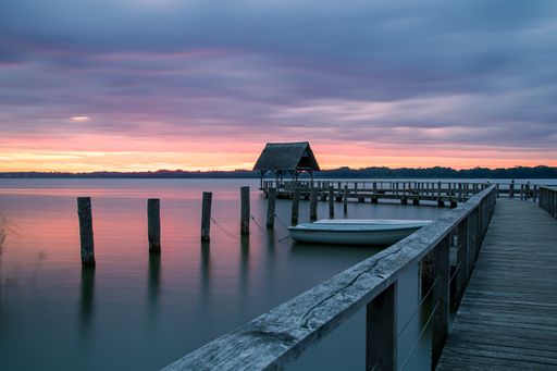A beautiful shot of a long wooden pier with the sunset sky colors reflecting in the water