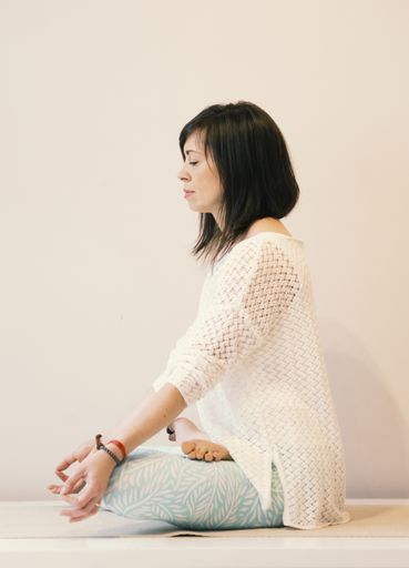 A vertical shot of a young girl doing a yoga pose on the yoga mat. Meditation at home