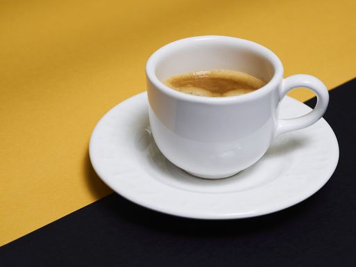 A top view of a cup of espresso coffee on a yellow-black background