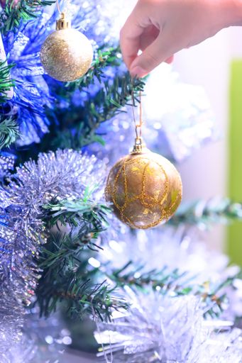 A vertical shot of a golden ball on the decorated Christmas tree. Isolated abstract background