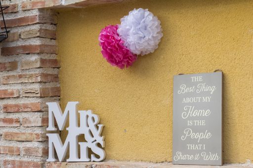 A closeup of the pom poms flower decoration with the word "Mr &Mrs" on the wall