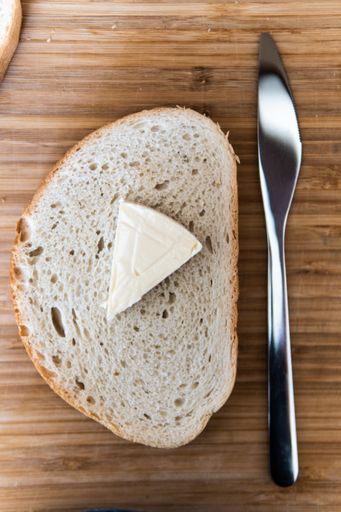 A vertical shot of a breakfast: a slice of bread with a butter on top and a knife