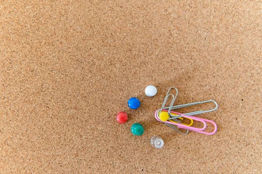 A closeup shot of paper clips and clips on a wooden board